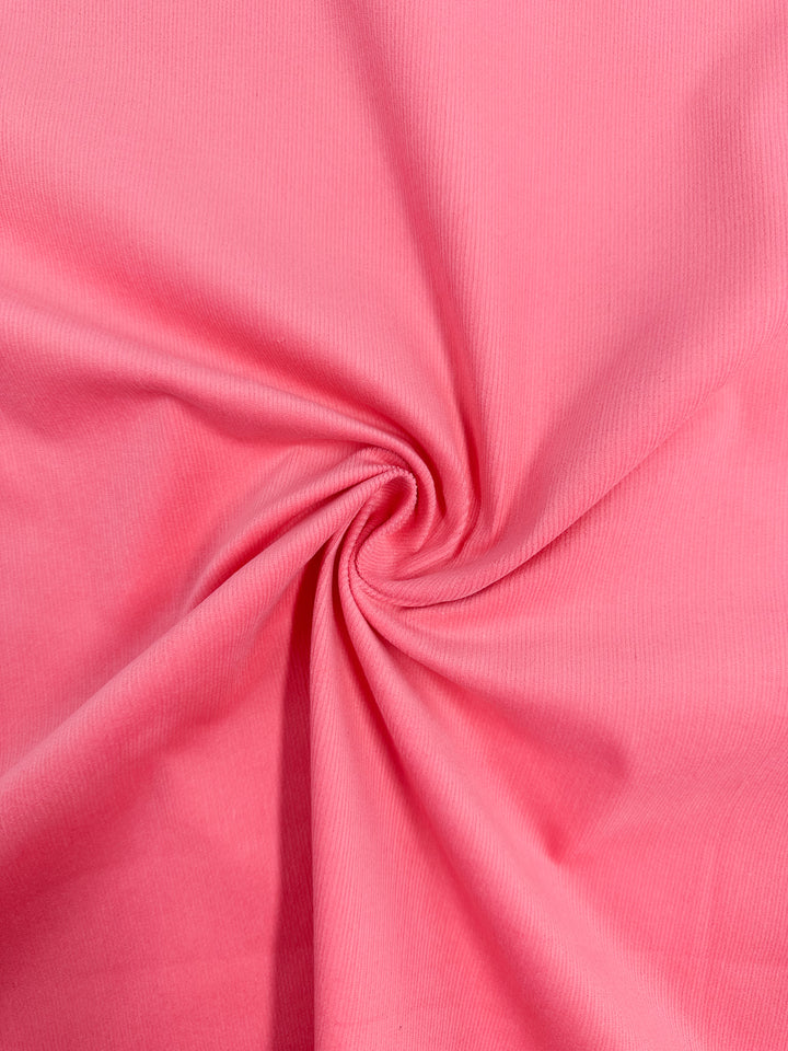 The Micro Wale Corduroy - Camellia Rose from Super Cheap Fabrics features a spiral twist design creating soft folds and shadows. Its 147cm-wide ribbed texture is smooth and slightly ribbed, evoking the feel of cozy winter clothing.