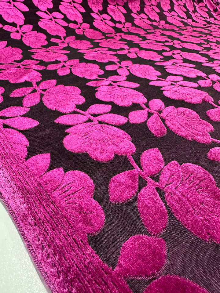 The Burnout Velvet - Cactus Flower by Super Cheap Fabrics features a luxurious 160cm fabric with vibrant pink floral patterns on a dark backdrop. The textured flowers offer a bold contrast, showcasing intricate details and rich colors in sophisticated style.