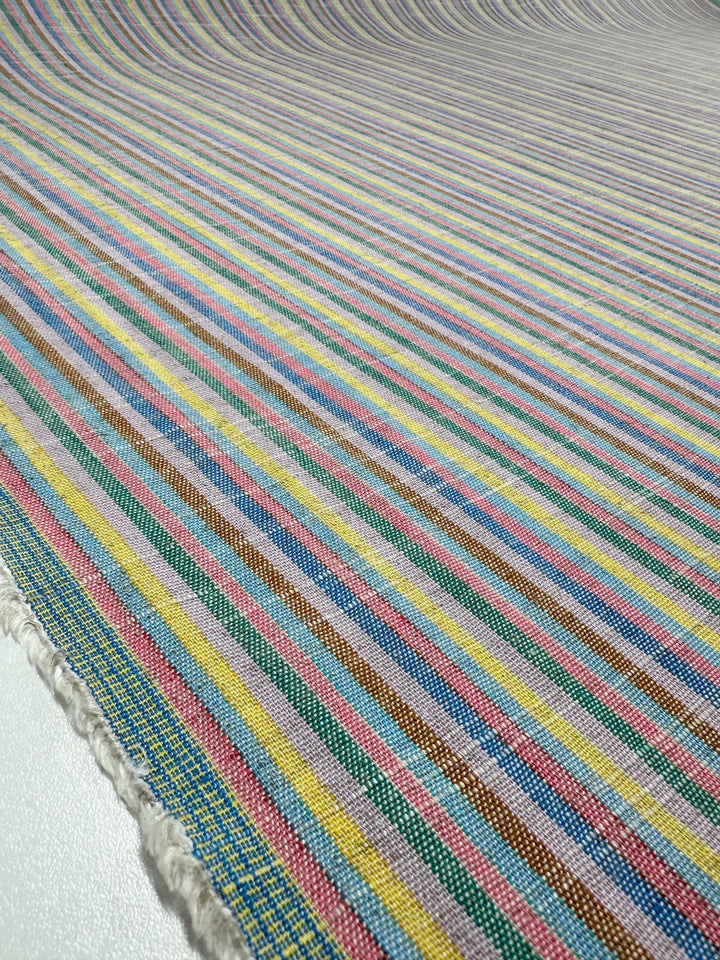 The image features a 143cm Linen Blend - Tropicana fabric by Super Cheap Fabrics, showcasing horizontal stripes in pink, blue, yellow, green, and brown. The woven texture gives it a vintage look with detailed patterns.