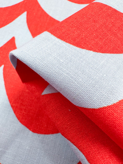 Close-up of folded Linen Blend - Smile - 136cm by Super Cheap Fabrics, showcasing a Cherry Tomato hue with vibrant red and white curves. The detailed textile texture features an intricate weave, perfect for stylish home decor.