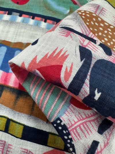 The Super Cheap Fabrics' Linen Blend - Rivers, 145cm-wide fabric features abstract geometric patterns in pink, blue, and green tones. This colorful linen cotton blend is slightly folded to showcase texture ideal for vibrant and multi-use projects.