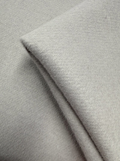 A close-up of Super Cheap Fabrics' Wool Cashmere - Windchime (150cm) shows its soft, light grey material neatly folded. The fuzzy texture highlights its cozy warmth—ideal for elegant, luxurious creations.