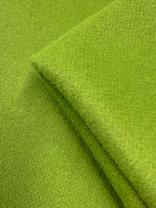 A close-up of Super Cheap Fabrics' Wool Cashmere - Titanite (154cm): textured, bright green heavyweight wool with a slightly fuzzy, luxuriously soft surface and a visible folded edge.