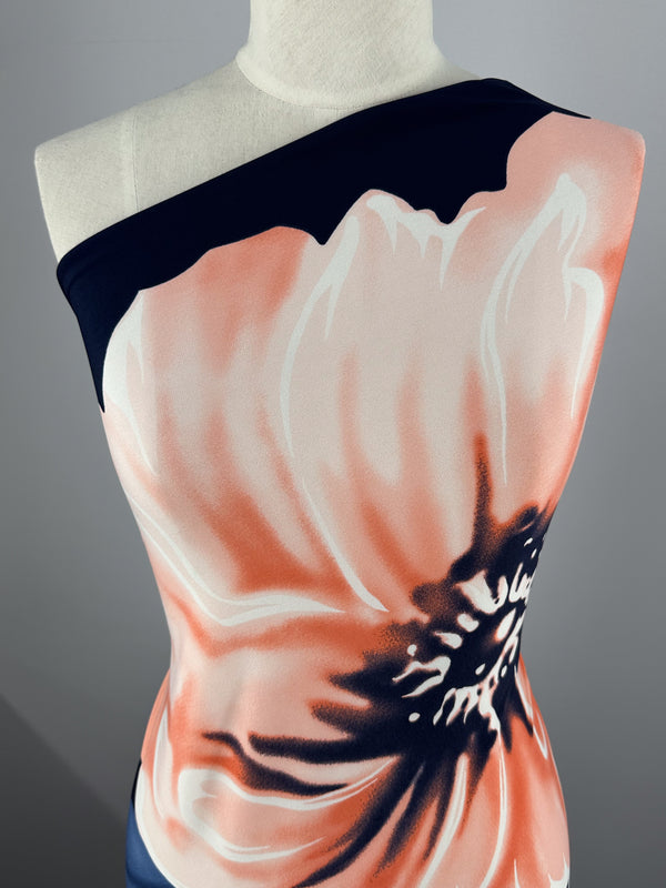 A mannequin wears an asymmetrical top in black and white, crafted from smooth, medium-weight Printed Lycra by Super Cheap Fabrics. It features a two-way stretch and a large, vibrant pink and black floral print with bold contrasts for comfort and style.