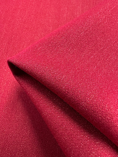 Close-up of a folded piece of Super Cheap Fabrics' Stretch Denim - Scooter, 145cm wide, with a smooth, slightly textured surface. The medium weight material appears durable and well-knit, showcasing a vibrant, deep red color.