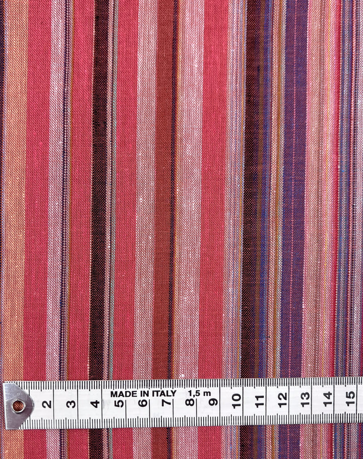 This is a detailed view of the Linen Blend - Colombo fabric by Super Cheap Fabrics, featuring vertical stripes in diverse shades of red, pink, and brown. A measuring tape labeled "Made in Italy" runs along the bottom edge, highlighting 15 centimeters of elegantly woven fabric.