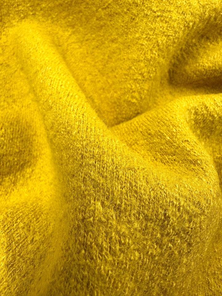 Close-up of Super Cheap Fabrics' Boiled Wool - Hot Spot - 145cm, a plush yellow wool-viscose blend with gentle folds and visible fibers. It has a vibrant hue that suggests warmth and comfort.