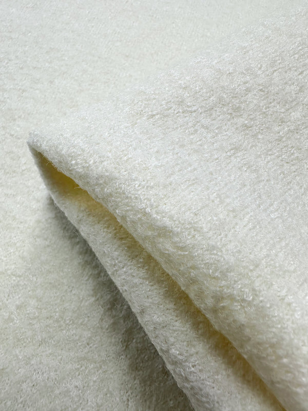 Close-up of a soft ivory textured fabric from Super Cheap Fabrics, showcasing the fluffy, plush surface of their Boiled Wool. The wool-viscose blend appears folded, highlighting its 150cm width and cozy thickness.