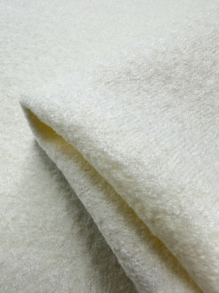 Close-up of a soft ivory textured fabric from Super Cheap Fabrics, showcasing the fluffy, plush surface of their Boiled Wool. The wool-viscose blend appears folded, highlighting its 150cm width and cozy thickness.