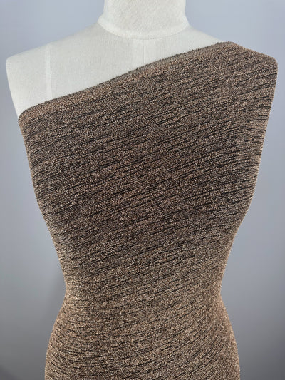 A mannequin presents a textured one-shoulder garment crafted from Super Cheap Fabrics' "Metallic Lycra - Golden - 150cm." The medium-weight lycra adds structure, complementing the form against a plain light gray background, highlighting its sleek design.