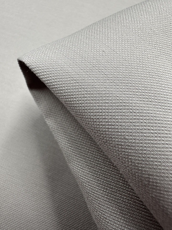 Close-up of folded "Suiting - Lilac Ash - 144cm" fabric by Super Cheap Fabrics, featuring a textured woven pattern. This light to medium weight bamboo fabric showcases crisp edges and a subtle sheen.