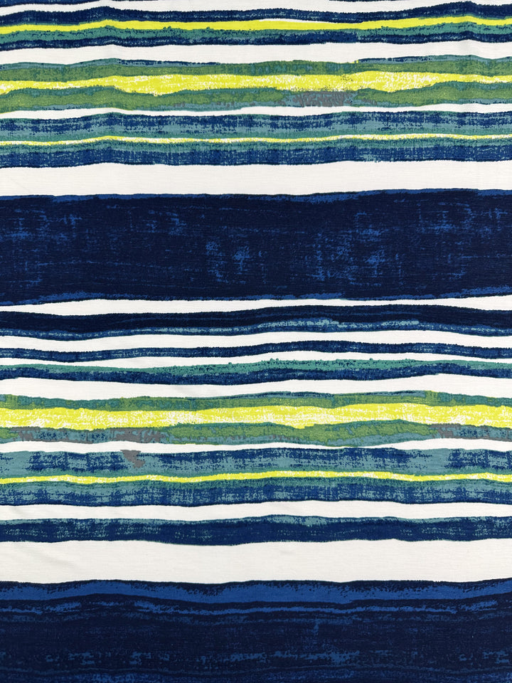 The Printed Lycra - Ocean Stripe from Super Cheap Fabrics showcases uneven horizontal stripes in shades of blue, green, and white. These summer-inspired stripes vary in thickness and texture, creating a layered look across the 145cm fabric.