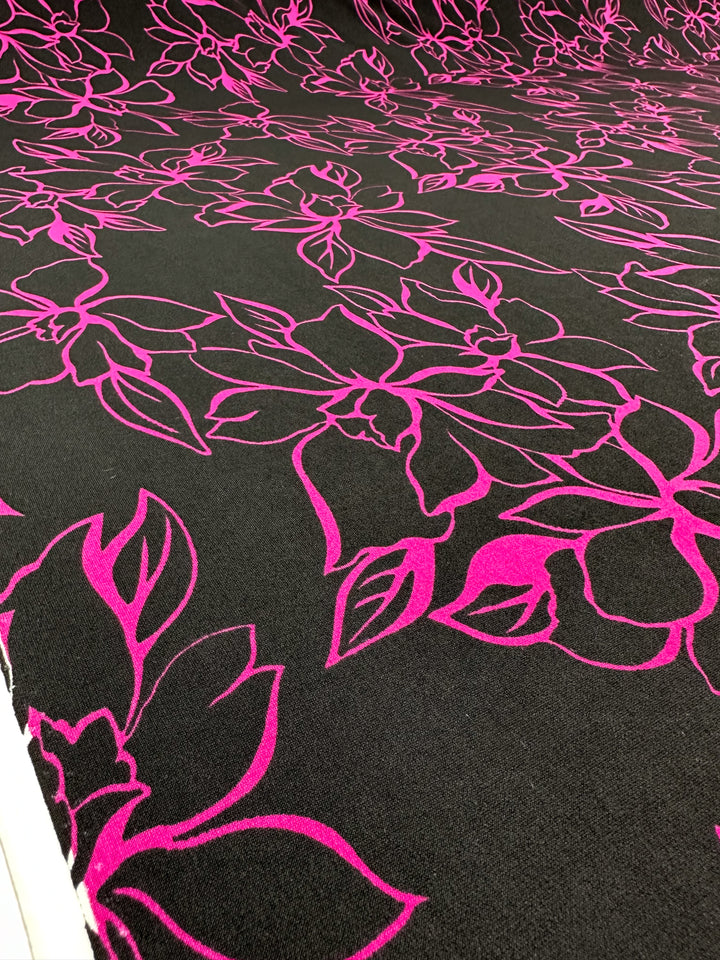 Close-up of Super Cheap Fabrics' Printed Lycra - Devour (145cm), a Polyester/Spandex fabric featuring vibrant pink outlined flowers and leaves intricately printed on a two-way stretch material.