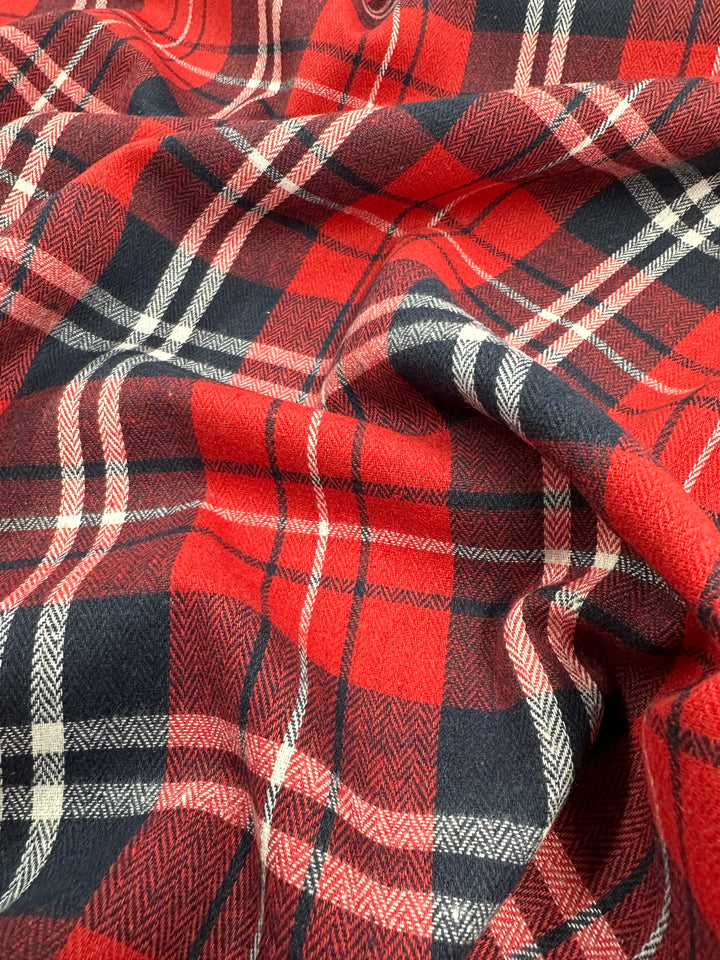 Close-up of the "Suiting - Trad Tartan - 147cm" fabric from Super Cheap Fabrics. The image highlights the intricate details of the woven texture and intersecting lines, showcasing the classic checkered pattern often seen in traditional Scottish kilts and garments, typically crafted in a lightweight fabric perfect for formal suits.