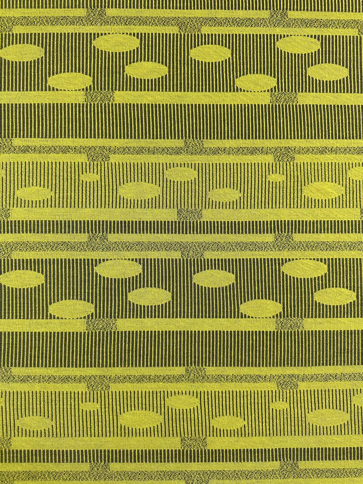 The Super Cheap Fabrics Jacquard Knit in Chartreuse (138cm) features a textured fabric with green and yellow horizontal stripes and a geometric pattern of vertical lines and oval shapes. It offers stretch for comfort while retaining a woven look.