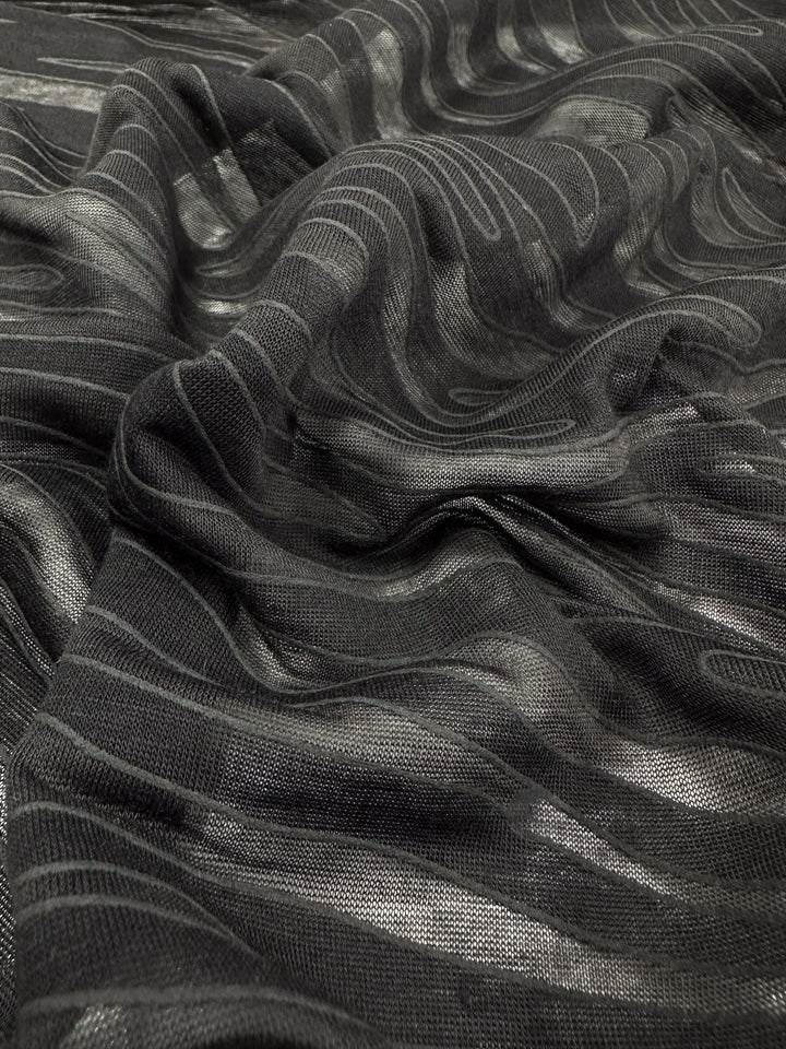 Close-up of Super Cheap Fabrics' Burnout Jersey - Zebra (160cm), featuring swirling knit patterns like a zebra print. The subtly reflective material adds gentle highlights and shadows, accentuating the undulating design.