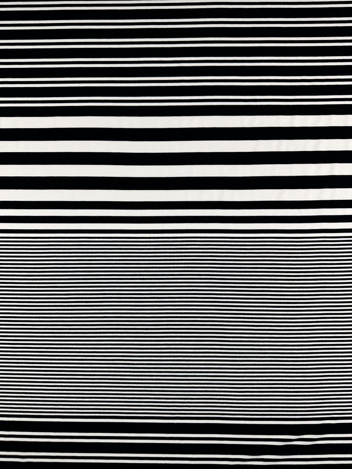 The Viscose Jersey - Paralello - 160cm by Super Cheap Fabrics showcases a dynamic pattern of horizontal black and white stripes, with wider ones on the top half and thin, closely spaced stripes on the bottom half, all on a soft, stretchy fabric.