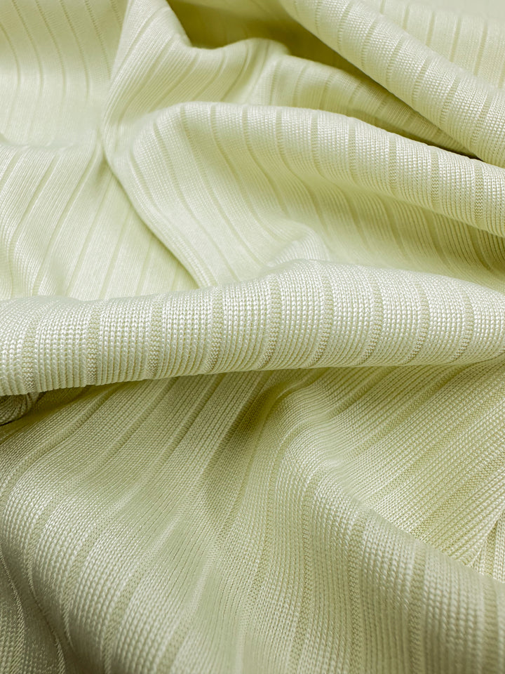 Close-up of Super Cheap Fabrics' Rib Knit - Sylvan Green, 175cm wide. This medium-weight fabric features a soft, flowing texture with slight gathers for gentle folds and a subtle sheen, enhancing its stretchy comfort and highlighting the vertical ribbed pattern.