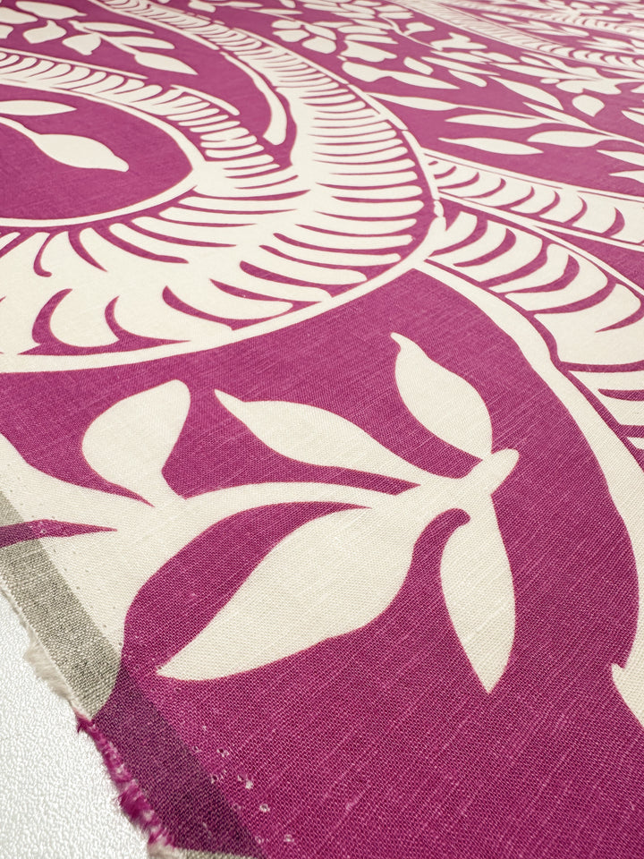 Close-up of the lightweight Linen Blend - Rose Violet, 138cm by Super Cheap Fabrics, showing an intricate cream floral and leaf pattern on a purple background with bold curved lines. The elegant design's fabric edges are visible at the corner.