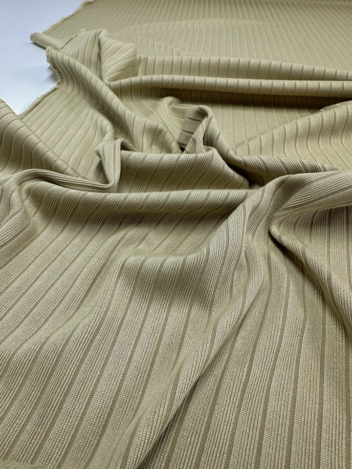 Super Cheap Fabrics' Rib Knit in Hay, 170cm wide, features soft folds of medium weight beige fabric with vertical ribbing for added structure and elegance.