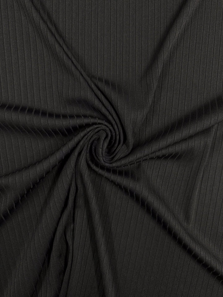 Close-up of Super Cheap Fabrics' Rib Knit - Black, a medium-weight fabric featuring subtle vertical ribbing. The stretchy and comfortable material is gathered at the center, forming an enchanting spiral pattern. Width: 170cm.