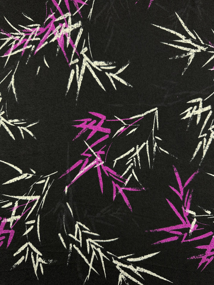 Super Cheap Fabrics offers "Textured Knit - Bamboo - 145cm," a medium weight black fabric featuring an abstract pattern of scattered white and pink bamboo leaves. The vibrant design, characterized by sharp angular lines, provides a generous stretch for versatile uses.