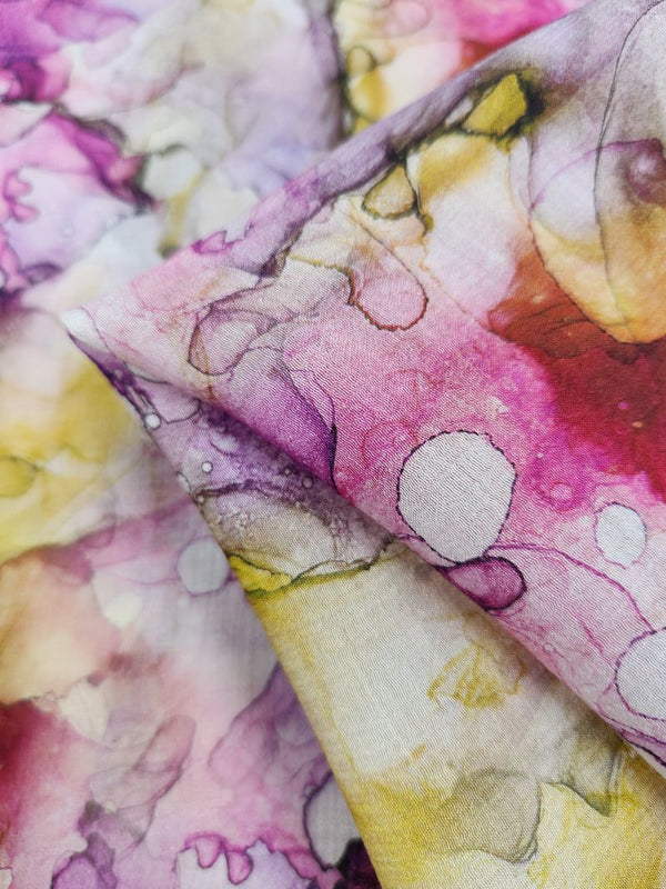 Close-up of the Designer Cotton - Blist - 150cm by Super Cheap Fabrics, showcasing its breathable fabric with a watercolor-inspired pattern in pink, purple, yellow, and white shades. This design offers a fluid and abstract look with overlapping colors and soft edges, making it perfect for luxury sewing projects.