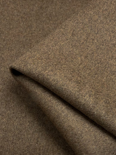 Close-up of a thick *Wool Cashmere - Malt Ball - 150cm* from *Super Cheap Fabrics* with a soft, smooth texture. The material is slightly folded, showcasing its thickness and subtle color variations. The brown hue appears warm and earthy like a malt ball, suggesting potential use in clothing or home furnishings.