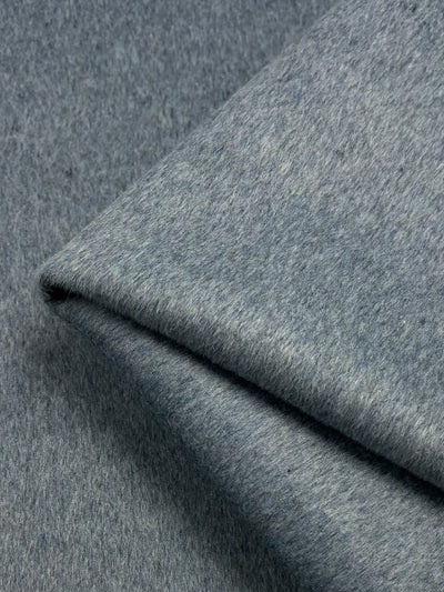Close-up image of a folded piece of gray fabric, showcasing its soft, felt-like texture. The Wool Cashmere - Rain Washed - 150cm by Super Cheap Fabrics appears smooth with a slight heathered pattern in light and dark gray tones, ideal for outer coats and jackets.