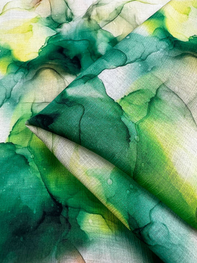 The Designer Cotton - Fern - 150cm by Super Cheap Fabrics mirrors the beauty of abstract watercolor art, with its luxurious design reminiscent of high-end sewing projects. It displays vibrant hues of green and yellow gracefully merging across the fabric. The pattern includes fluid shapes and overlapping layers that evoke a sense of depth and dynamic movement characteristic of designer cotton fabrics.