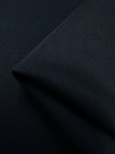 Close-up view of the navy blazer ponte fabric from Super Cheap Fabrics, featuring a smooth texture and showing a fold at an angle. The 100% polyester material appears soft and tightly woven, highlighting its detailed fibers and uniform color.