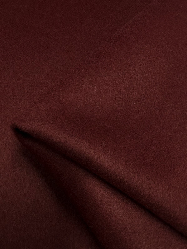 Close-up image of a piece of rich, Fired Brick-colored, extra heavy weight Wool Cashmere fabric from Super Cheap Fabrics, folded diagonally to highlight its soft, smooth texture and luxurious appearance. The material appears thick and sumptuous, ideal for warm outer coats or upholstery; dry clean only. The fabric width is 150cm.